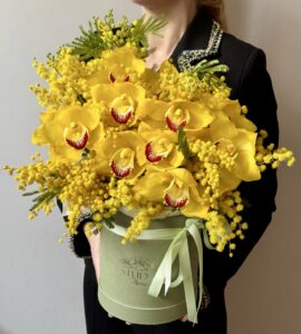 Flowers in a box with cymbidium and mimosa for a girl