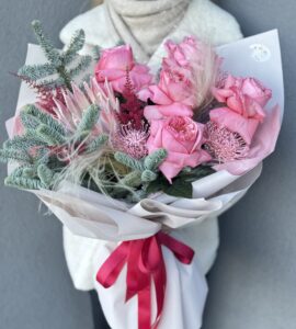 Winter bouquet with spruce, protea, and roses